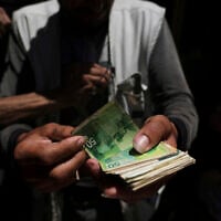 A Palestinian vegetable merchant shows worn-out Israeli currency, July 9, 2025, in Gaza City. (AP/Jehad Alshrafi)