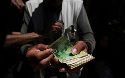 A Palestinian vegetable merchant shows worn-out Israeli currency, July 9, 2025, in Gaza City. (AP/Jehad Alshrafi)