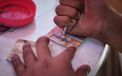 A Palestinian man repairs worn-out Israeli currency, July 9, 2025, in Gaza City. (AP Photo/Jehad Alshrafi)