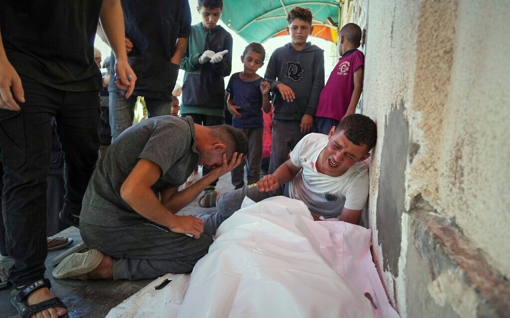 Relatives mourn over the bodies of Manal Abd Rabbo and her sister Fatima, who were among 13 people, including two women and eight children, reported killed in an Israeli strike while waiting to receive nutritional supplements at a Project Hope-run medical clinic in Deir al-Balah, Gaza Strip, July 10, 2025. (AP Photo/Abdel Kareem Hana)