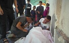 Relatives mourn over the bodies of Manal Abd Rabbo and her sister Fatima, who were among 13 people, including two women and eight children, reported killed in an Israeli strike while waiting to receive nutritional supplements at a Project Hope-run medical clinic in Deir al-Balah, Gaza Strip, Thursday, July 10, 2025. (AP Photo/Abdel Kareem Hana)