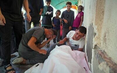 Relatives mourn over the bodies of Manal Abd Rabbo and her sister Fatima, who were among 13 people, including two women and eight children, reported killed in an Israeli strike while waiting to receive nutritional supplements at a Project Hope-run medical clinic in Deir al-Balah, Gaza Strip, Thursday, July 10, 2025. (AP Photo/Abdel Kareem Hana)