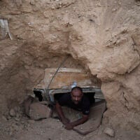Ahmad Abu Ganima poses for a portrait in the window of the minibus buried in the earth, a makeshift bomb shelter his family uses in Khashem Zaneh, an unrecognized Bedouin village in the Negev Desert, southern Israel, July 2, 2025. (Maya Alleruzzo/AP)