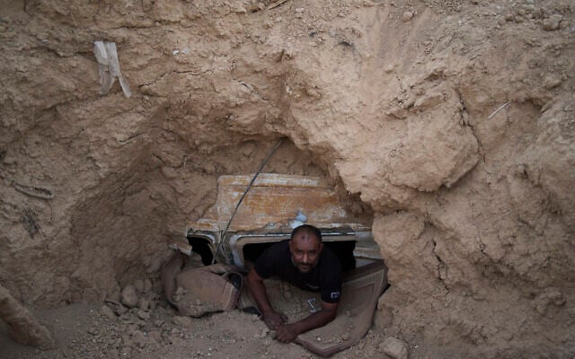 Ahmad Abu Ganima poses for a portrait in the window of the minibus buried in the earth, a makeshift bomb shelter his family uses in Khashem Zaneh, an unrecognized Bedouin village in the Negev Desert, southern Israel, July 2, 2025. (Maya Alleruzzo/AP)