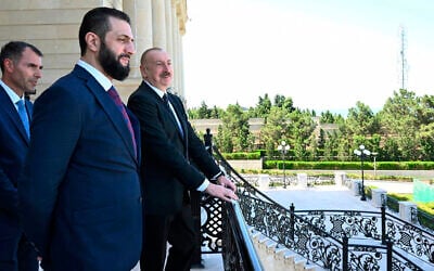 Azerbaijani President Ilham Aliyev, right, and Syria's interim president, Ahmad al-Sharaa, second left, stand on the balcony during their meeting in Baku, Azerbaijan, July 12, 2025. (Azerbaijani Presidential Press Office via AP)
