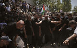 Mourners gather around the graves of Palestinian-American Saif Musallet, 20, and Mohammed al-Shalabi during their funeral in the West Bank village of Al-Mazraa ash-Sharqiya on Sunday, July 13, 2025. (AP/Leo Correa)