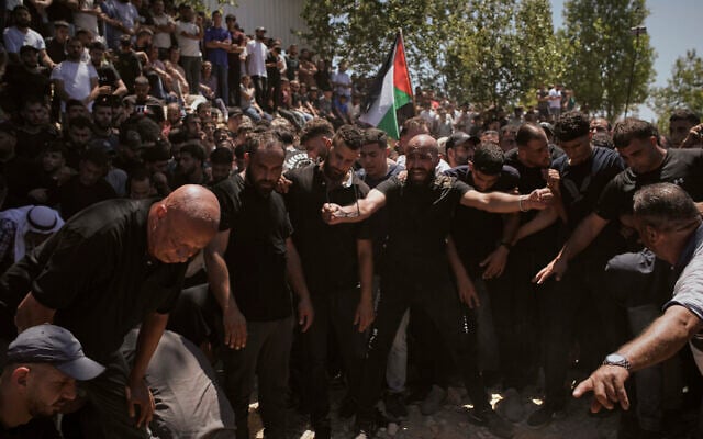 Mourners gather around the graves of Palestinian-American Saif Musallet, 20, and Mohammed al-Shalabi during their funeral in the West Bank village of Al-Mazraa ash-Sharqiya on Sunday, July 13, 2025. (AP/Leo Correa)