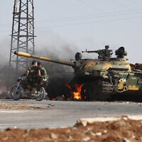 Syrian government soldiers on a motorcycle pass by a burning tank on the outskirts of Sweida city, where clashes erupted between Druze militias and Sunni Bedouin clans, in southern Syria, July 14, 2025. (AP/Omar Sanadiki)