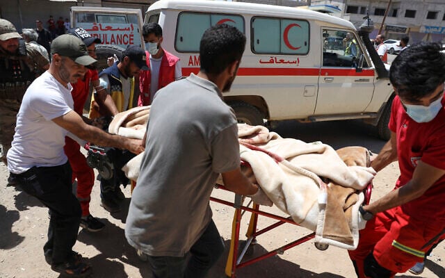 Red Crescent volunteers carry a government soldier injured in Sweida city during clashes between the government forces and Druze militias at a clinic in Busra al-Harir village, southern Syria, Tuesday, July 15, 2025. (AP Photo/Omar Albam)