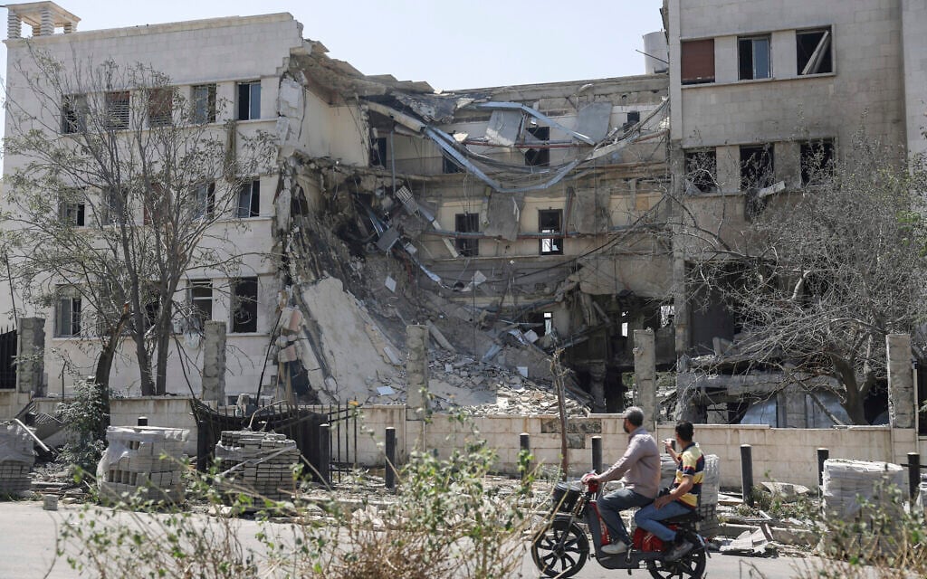 People pass in front the Syrian Defense Ministry building which was heavily damaged by Israeli airstrikes in Damascus, Syria, July 17, 2025. (AP/Ghaith Alsayed)