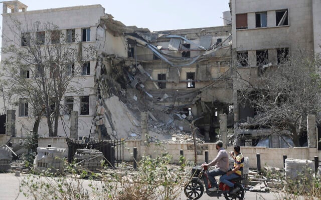People pass in front the Syrian Defense Ministry building which was heavily damaged by Israeli airstrikes in Damascus, Syria, July 17, 2025. (AP/Ghaith Alsayed)