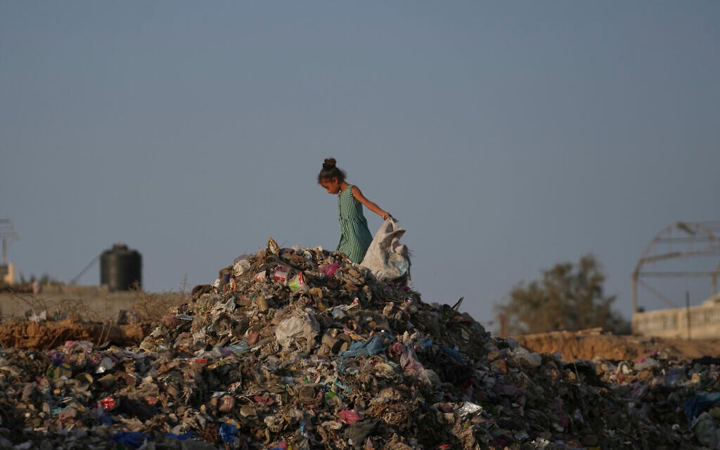 A Palestinian girl searches through a landfill for firewood, plastic, and canned goods in Al-Zawaideh, central Gaza Strip, July 17, 2025. (AP Photo/Abdel Kareem Hana)
