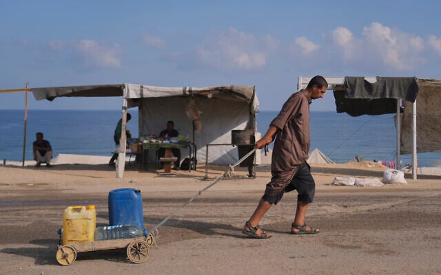 A man pulls a cart loaded with jerrycans and plastic bottles with water after collecting it at a camp for displaced people in Deir al-Balah, central Gaza Strip, July 19, 2025. (AP Photo/Abdel Kareem Hana)