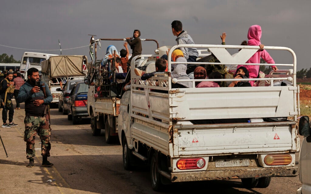 Syrian Bedouin families ride in the back of trucks carrying their belongings, in a convoy led by Red Crescent vehicles in Busra al-Harir, heading to Daraa after being evacuated from Sweida following more than a week of violent clashes, July 21, 2025. (Malek Khattab/AP)