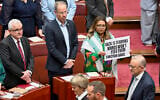 Greens Senator Mehreen Faruqi holds a placard as Australian Prime Minister Anthony Albanese walks in the Senate chamber for the opening of the 48th Federal Parliament at Parliament House in Canberra, Australia, July 22, 2025. (Lukas Coch/AAP Image via AP)