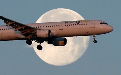 A Vueling Airbus A321 approaches for landing in Lisbon at sunrise, while the moon sets in the background, February 7, 2023. (Armando Franca/AP)