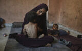 Naima Abu Ful holds her malnourished 2-year-old child, Yazan, at their home in the Shati refugee camp in Gaza City on July 23, 2025. (AP Photo/Jehad Alshrafi)