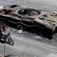 Druze militiamen ride a motorcycle past a destroyed military vehicle following last week's sectarian clashes in the Druze-majority town of Sweida, Syria, July 25, 2025. (AP Photo/Omar Sanadiki)