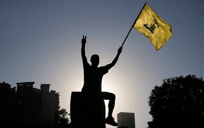 A Hezbollah supporter holds up a Hezbollah flag in front of the headquarters of the UN Economic and Social Commission for Western Asia (ESCWA) in Beirut, Lebanon, July 26, 2025. (AP Photo/Bilal Hussein)