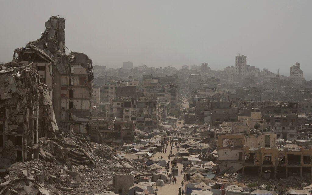 People walk along a street lined with destroyed buildings in the Gaza Strip, Tuesday, July 29, 2025. (AP/Jehad Alshrafi)