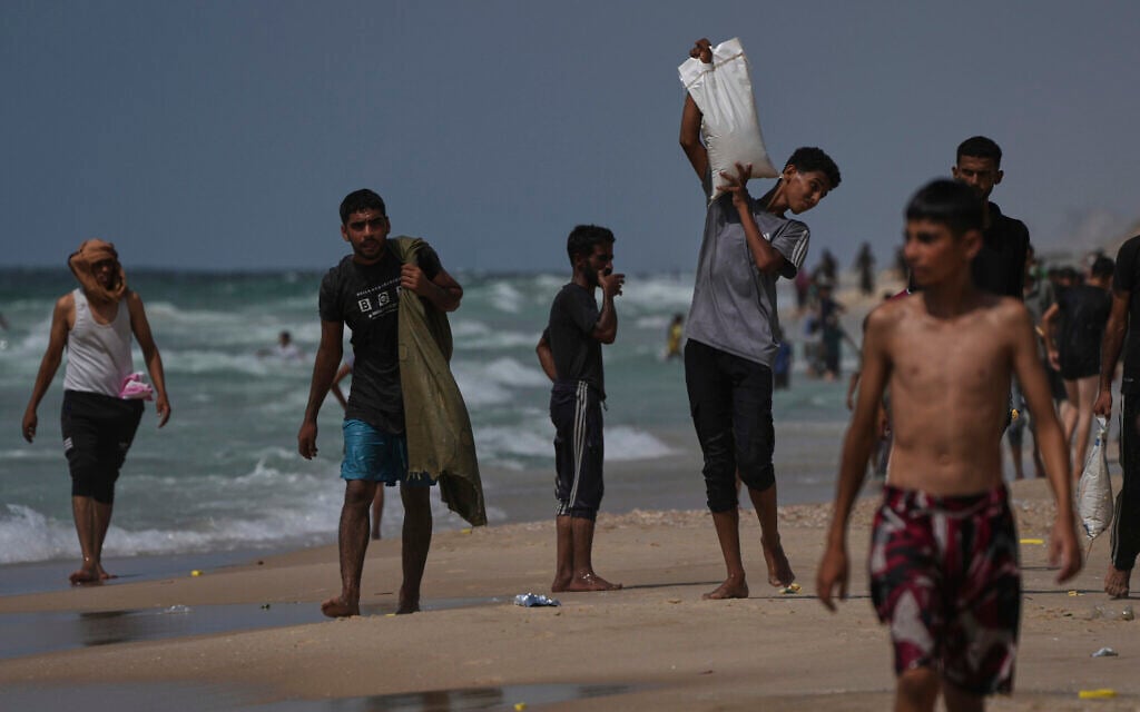 Palestinians collect aid that landed in the Mediterranean Sea after being airdropped over central Gaza, at the shore of Zawaida, Gaza Strip Tuesday, July 29, 2025. (AP/Abdel Kareem Hana)