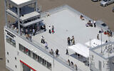 People take shelter on the roof of a fire station in Mukawa town, Hokkaido, northern Japan Wednesday, July 30, 2025, after a powerful earthquake in Russia's Far East prompted tsunami alert in parts of Japan. (Kyodo News via AP)