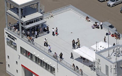 People take shelter on the roof of a fire station in Mukawa town, Hokkaido, northern Japan Wednesday, July 30, 2025, after a powerful earthquake in Russia's Far East prompted tsunami alert in parts of Japan. (Kyodo News via AP)