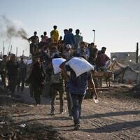Palestinians ride on trucks from a humanitarian aid convoy bound for Gaza City from the northern Gaza Strip, as others carry sacks of flour unloaded from the vehicles, Thursday, July 31, 2025. (AP Photo/Jehad Alshrafi)