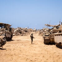An IDF soldier is seen next to armored vehicles in northern Gaza's Beit Hanoun, July 30, 2025. (Emanuel Fabian/Times of Israel)