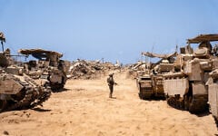 An IDF soldier is seen next to armored vehicles in northern Gaza's Beit Hanoun, July 30, 2025. (Emanuel Fabian/Times of Israel)