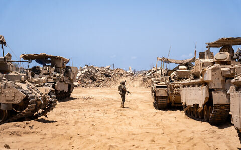 An IDF soldier is seen next to armored vehicles in northern Gaza's Beit Hanoun, July 30, 2025. (Emanuel Fabian/Times of Israel)