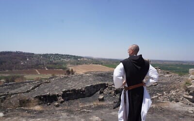 Brother Athanase, a Catholic monk of a monastery in Latrun, looks out on the damage caused by wildfires to the monastery's vineyards and olive groves, on July 16, 2025. (Charlie Summers/Times of Israel)