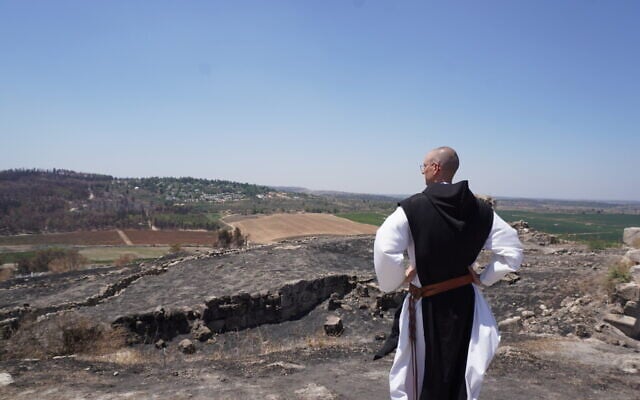 Brother Athanase, a Catholic monk of a monastery in Latrun, looks out on the damage caused by wildfires to the monastery's vineyards and olive groves, on July 16, 2025. (Charlie Summers/Times of Israel)