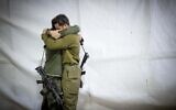 IDF soldiers embrace at the funeral of reservist Tzvika Lavi at the Mount Herzl Military Cemetery in Jerusalem, December 12, 2023. (Yonatan Sindel/Flash90)