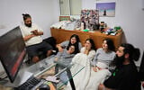 An Israeli family watches the TV from their protected room in central Israel as the country is attacked by ballistic missiles from Iran, June 13, 2025. (Nati Shohat/FLASH90)