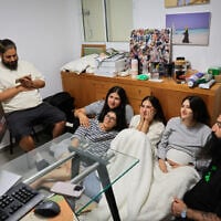 An Israeli family watches the TV from their protected room in central Israel as the country is attacked by ballistic missiles from Iran, June 13, 2025. (Nati Shohat/FLASH90)