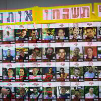 People walking next to pictures of hostages held by terrorists in Gaza, in Jerusalem, July 2, 2025 (Yonatan Sindel/Flash90)