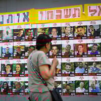 People walking next to pictures of Israelis held hostage by Hamas terrorists in Gaza, in Jerusalem, July 2, 2025. (Yonatan Sindel/Flash90)