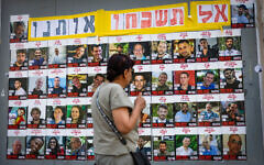 People walking next to pictures of Israelis held hostage by Hamas terrorists in Gaza, in Jerusalem, July 2, 2025. (Yonatan Sindel/Flash90)