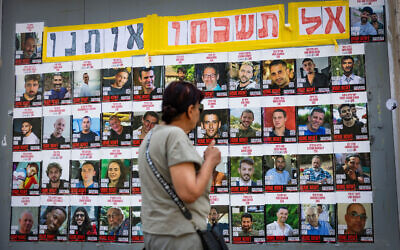 People walking next to pictures of Israelis held hostage by Hamas terrorists in Gaza, in Jerusalem, July 2, 2025. (Yonatan Sindel/Flash90)