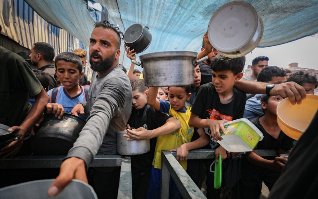 Palestinians receive meals from volunteers in the central Gaza Strip, on July 6, 2025. (Ali Hassan/Flash90)
