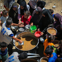 Palestinians receive hot meals from volunteers in Gaza City, on July 9, 2025. (Ali Hassan/Flash90)