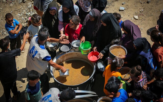 Palestinians receive hot meals from volunteers in Gaza City, on July 9, 2025. (Ali Hassan/Flash90)