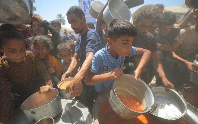Palestinians receive meals from volunteers in Deir al-Balah, in central Gaza Strip, on July 14, 2025. (Ali Hassan/Flash90)