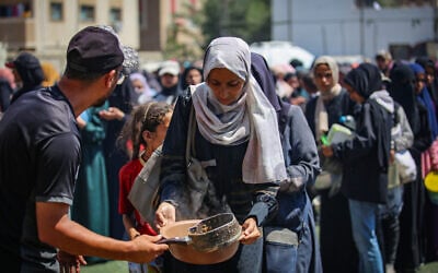Palestinians receive meals from volunteers in Gaza City, on July 25, 2025. (Ali Hassan/Flash90)