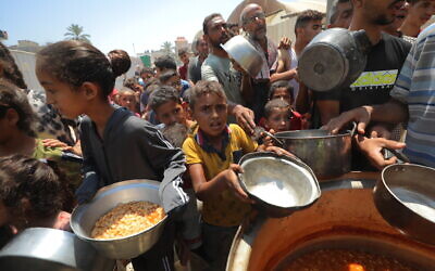 Palestinians receive meals from volunteers in Gaza City, on July 28, 2025. (Ali Hassan/Flash90)
