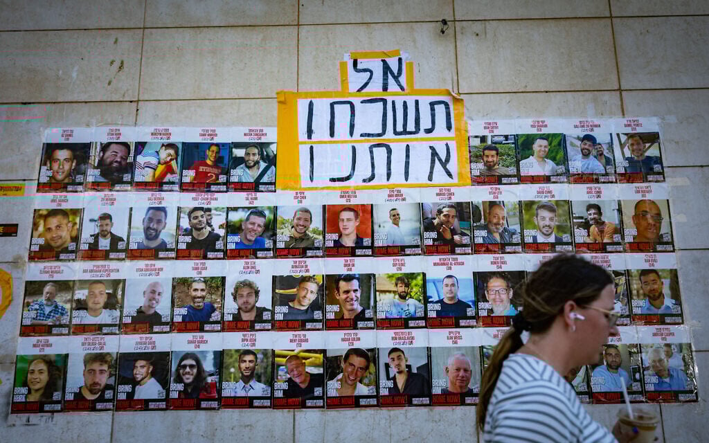 People walking next to pictures of Israelis held hostage by Hamas terrorists in Gaza, in Jerusalem, July 29, 2025. (Yonatan Sindel/Flash90)