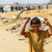 Palestinians carry food supplies they received from the US aid center in Rafah, in the southern Gaza Strip, July 30, 2025. (Photo by Abed Rahim Khatib/Flash90)
