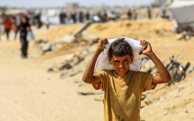 Palestinians carry food supplies they received from the US aid center in Rafah, in the southern Gaza Strip, July 30, 2025. (Photo by Abed Rahim Khatib/Flash90)