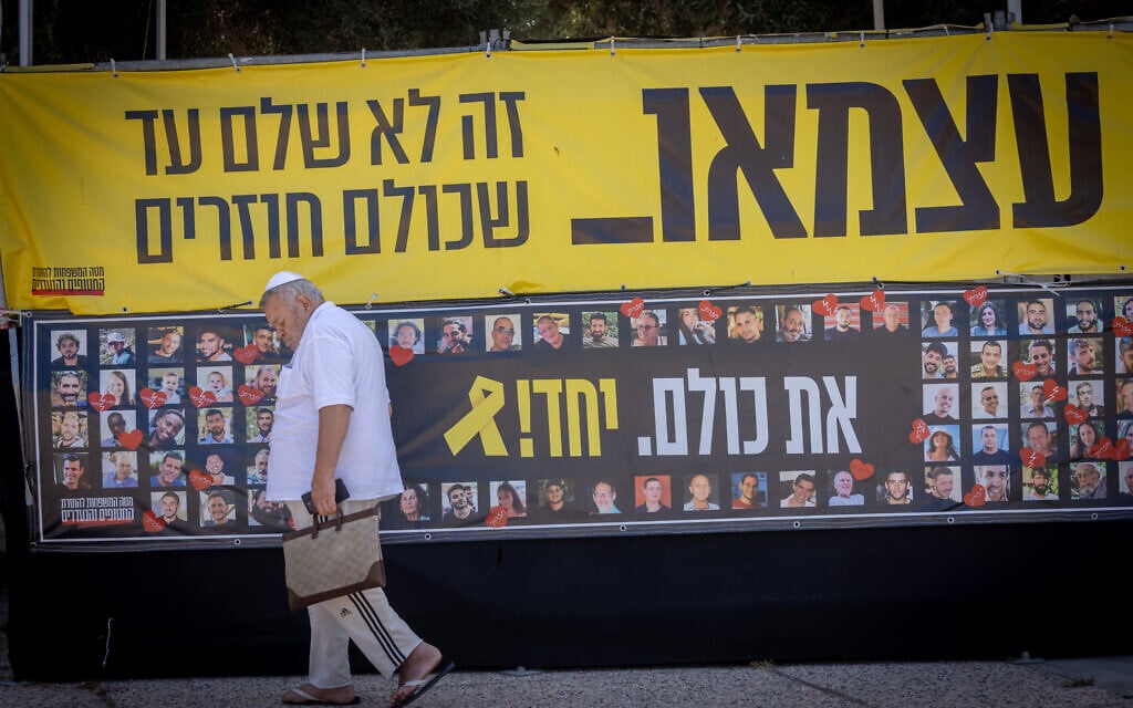 A man passes by a poster calling for the release of the hostages, at Tel Aviv's Hostages Square,July 30, 2025. (Miriam Alster/Flash90)